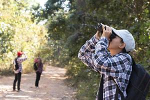 los niños asiáticos están usando binoculares para observar aves en el bosque tropical durante el campamento de verano, idea para aprender criaturas y animales salvajes e insectos fuera del aula. foto