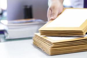 el enfoque suave del empleado de oficina o secretaria está preparando documentos y sobres marrones para aquellos interesados en licitar para la construcción de un gran edificio en una oficina. foto