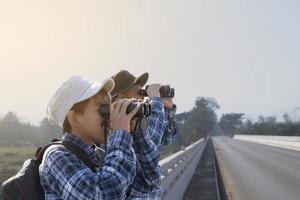 los niños asiáticos están usando binoculares para observar aves en el bosque tropical durante el campamento de verano, idea para aprender criaturas y animales salvajes e insectos fuera del aula. foto