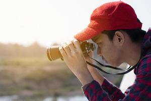 un niño asiático está usando binoculares para observar aves en el bosque tropical durante el campamento de verano, idea para aprender criaturas y animales salvajes e insectos fuera del aula. foto