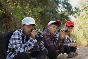 los niños asiáticos están usando binoculares para observar aves en el bosque tropical durante el campamento de verano, idea para aprender criaturas y animales salvajes e insectos fuera del aula. foto