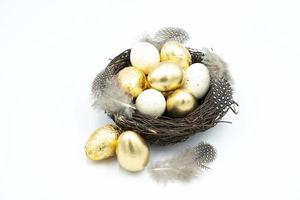 nido, huevos de pascua dorados y blancos foto