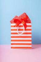 Shopping bag with gift boxes on colored background. Shopping concept. photo