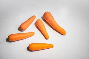 Fresh Carrot lay on white marble top table surface background with hard light and shadow on it. photo