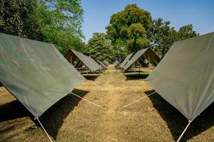 The simple and normal empty Canvas Tents in the row and column on the grass field at outdoor field in afternoon time. photo