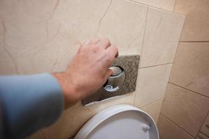 Hand of man push toilet flush press with two separate buttons. photo