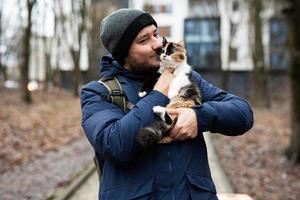 Man hold kitten in hands outdoor at park. photo