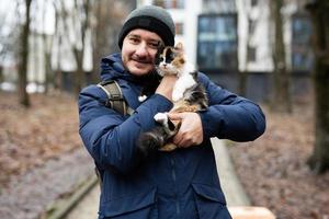 Man hold kitten in hands outdoor at park. photo