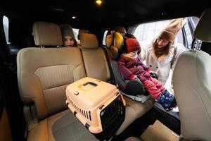 Mother and daughters with cat travel plastic cage carriage in car. photo