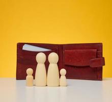 figurillas de madera de una familia en el fondo de una billetera marrón de cuero foto
