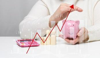 Ceramic piggy bank in a woman's hand and wooden figurines of a family. Savings, rising inflation photo