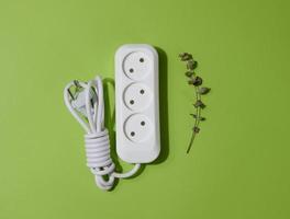 White plastic socket with cable on a green background, top view photo