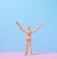 Wooden puppet man on a blue background, arms raised up photo