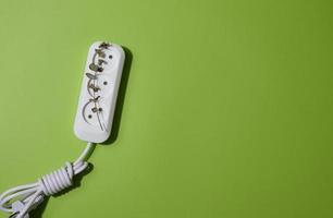 White plastic socket with cable on a green background, top view photo