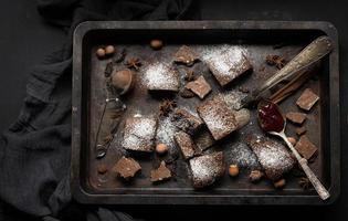 Baked square pieces of chocolate brownie sprinkled with powdered sugar on the table photo