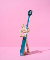 marioneta de madera sosteniendo un cepillo de dientes sobre un fondo rosa foto