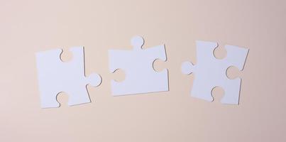 Empty white big puzzles on a beige background. Concept in business photo