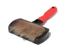 Plastic brush and combing out wool in animals and a tuft of gray cat hair on a white background photo