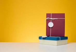 A stack of gift boxes wrapped in colorful paper on a yellow background. Happy Holidays photo