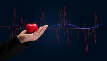 Male hand holding a red heart on a dark background photo