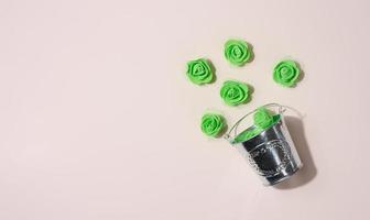 Miniature bucket and plastic green roses on a beige background photo