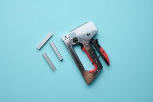 Household manual stapler and staples on a blue background, top view photo