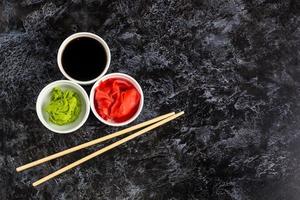 conjunto para sushi salsa de soja jengibre wasabi con palillos sobre fondo de piedra