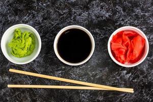 Set for sushi soy sauce ginger wasabi with chopstick on stone background photo