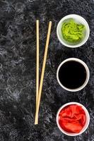 Set for sushi soy sauce ginger wasabi with chopstick on stone background photo