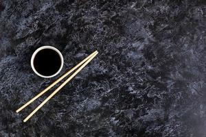 Japanese sushi chopsticks and soy sauce on black background. Top view with copyspace photo