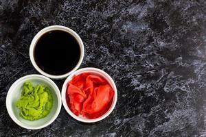 Set for sushi soy sauce ginger wasabi with chopstick on stone background photo