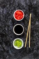 Set for sushi soy sauce ginger wasabi with chopstick on stone background photo