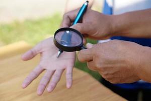 Closeup hand holds magnifying glass to inspect palm lines. Concept , palmistry, astrology. Foretelling, mystery, magic, fortune, fate. Prediction for future life , events.  Palmist predicting. photo