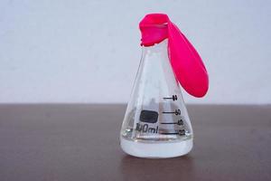 experimento científico, globo rosa plano sin aire encima de una botella de prueba transparente. primer paso del experimento sobre la reacción del aire o el gas.utilizando bicarbonato de sodio y vinagre.concepto, educación científica foto