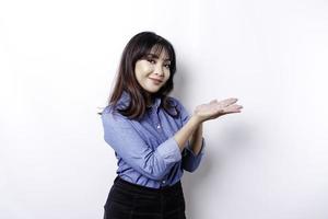 Excited Asian woman wearing blue shirt pointing at the copy space beside her, isolated by white background photo