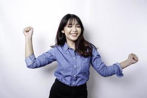 A young Asian woman with a happy successful expression wearing blue shirt isolated by white background photo