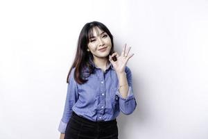 Excited Asian woman giving an OK hand gesture isolated by a white background photo