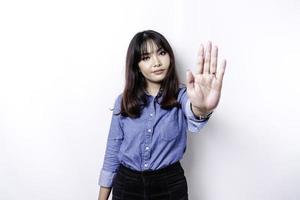 hermosa mujer asiática con camisa azul con pose de gesto de mano de parada o prohibición con espacio de copia foto