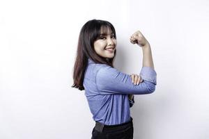 Excited Asian woman wearing a blue shirt showing strong gesture by lifting her arms and muscles smiling proudly photo