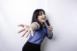 retrato de una mujer asiática despreocupada, divirtiéndose en el karaoke, cantando en el micrófono mientras está de pie sobre fondo blanco