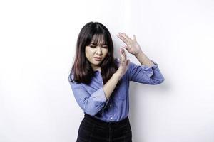 Young Asian woman isolated on white background, looks depressed, face covered by fingers frightened and nervous. photo