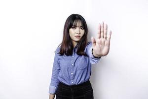 hermosa mujer asiática con camisa azul con pose de gesto de mano de parada o prohibición con espacio de copia foto