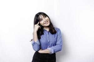 A thoughtful young woman dressed in blue shirt while looking aside, isolated by white background photo