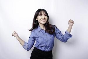 una joven asiática con una expresión feliz y exitosa que usa una camisa azul aislada de fondo blanco foto