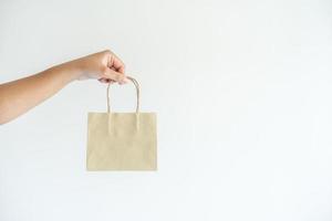 Woman hands carrying brown paper shopping bag. Concept of using recycle material to save the world and decrease pollution. photo