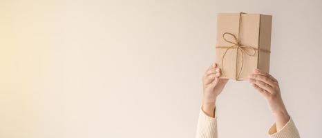 Woman hands holding present box with a ribbon bow. Minimalist concept of giving a present. photo