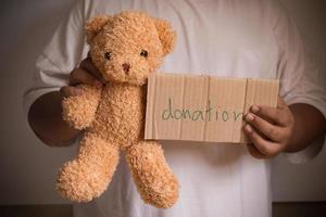 mano masculina que sostiene el oso de peluche para la donación foto