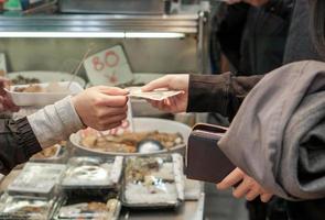 el primer plano y la cosecha de manos de los clientes compran y pagan billetes de yenes japoneses por alimentos en el mercado. foto