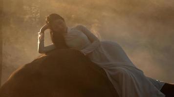 Handheld backlight shot, Young attractive asian woman in traditional costume lying on elephant, She closes her eyes to sleep, White smoke spread around her. video