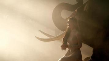 Handheld backlight shot, Young attractive asian woman in traditional costume with elephant, She combing her hair slowly with White smoke spread around her. video